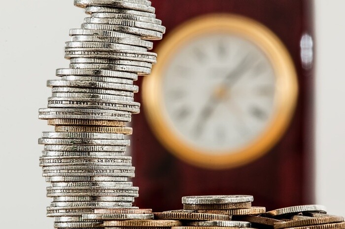 Stack of foreign coins and blurred clock image